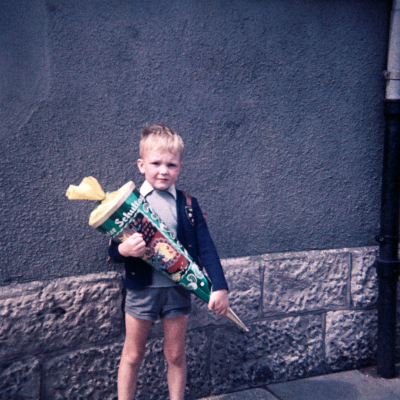 Ein Junge am Tage seiner Einschulung in die Erste Klasse an der Hohnsenschule in Hildesheim. Vor dem Haus Struckmannstraße/ Ecke Sprengerstraße in Hildesheim im Jahre 1967. Farbfoto.