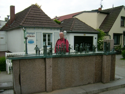 Farbfoto: Erwin Thomasius betrachtet die Plastik WARNMINNER ÜMGANG von Wolfgang Friedrich in der Alexandrinenstraße in Warnemünde im Jahre 2009. Fotograf: Bernd Paepcke.